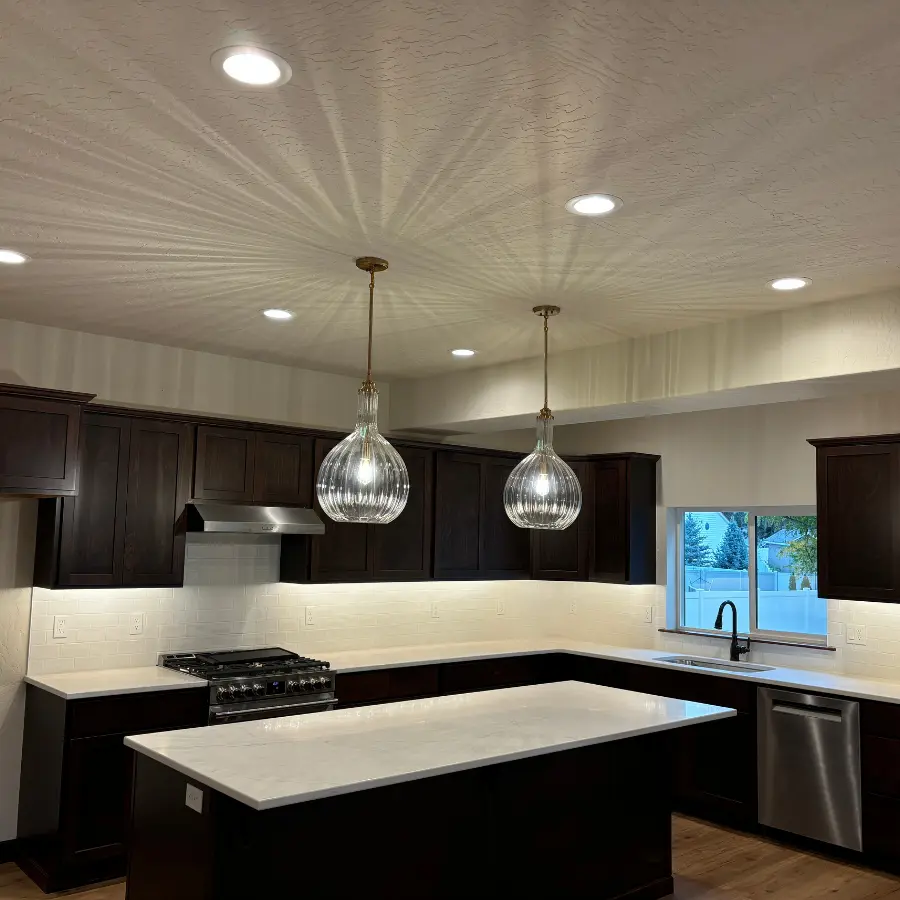 A spacious kitchen features dark wood cabinets with light countertops, a central island, and modern stainless steel appliances.